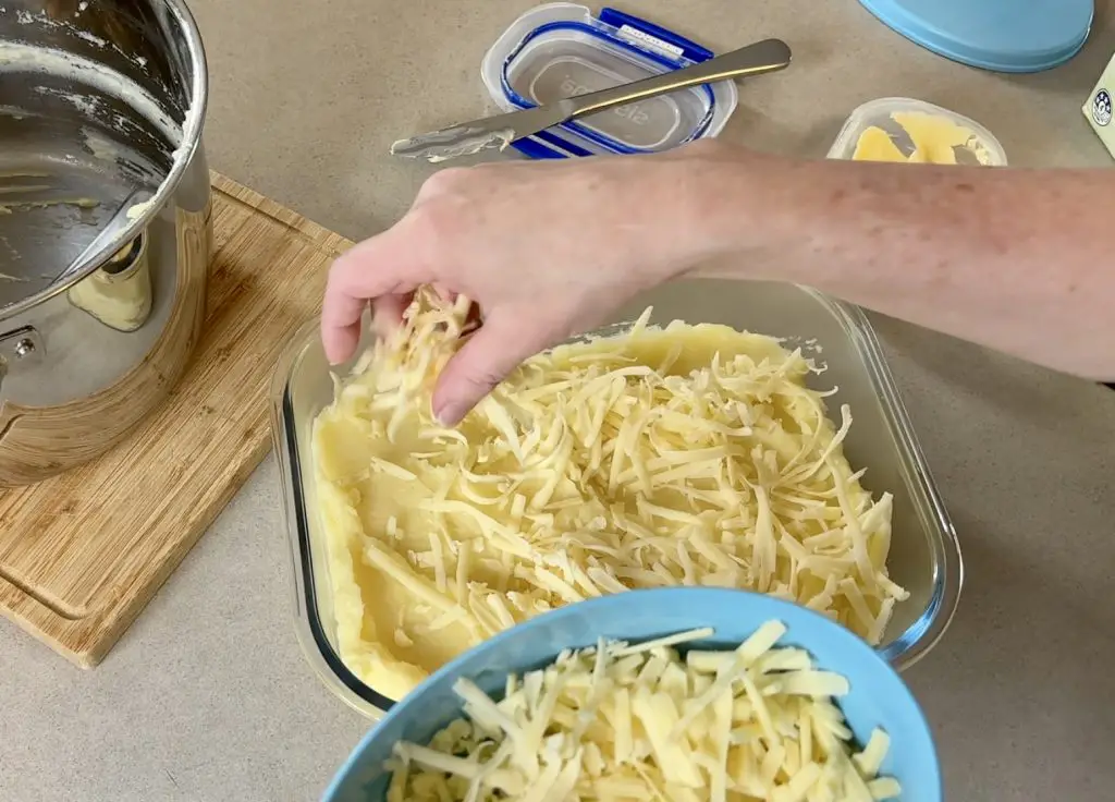 Adding cheese to cheesy mashed potato bake